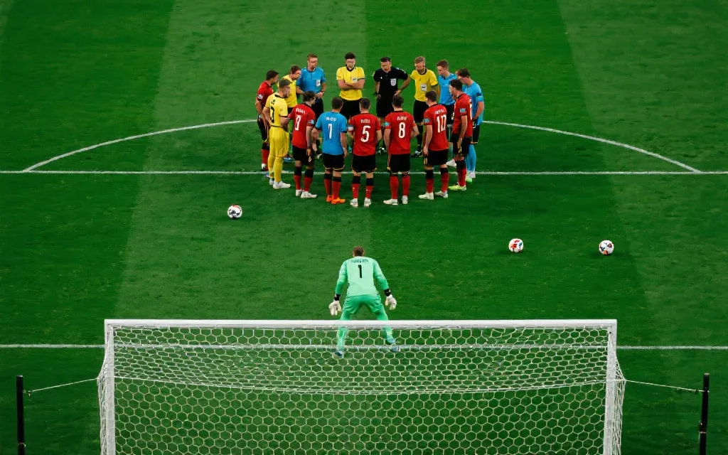 点球大战前球员围圈沟通与门将专注的战术氛围